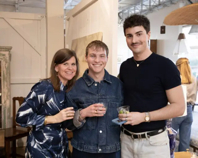 Three people smiling, two men and one woman, holding drinks.