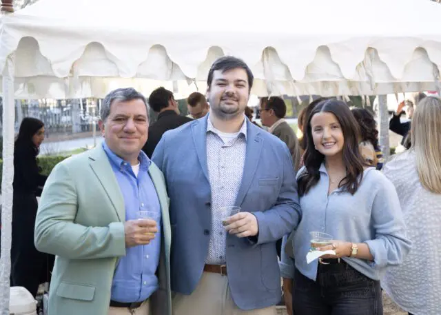 Three people holding drinks at an outdoor event.