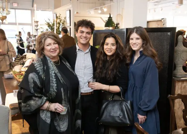 Four people posing for a photo indoors, with one woman wearing a black scarf with a snake print.