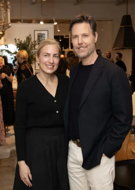 Man in navy blazer and woman in black cardigan and skirt