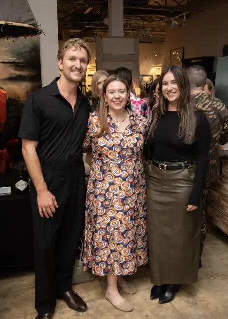 Man in black shirt and pants, woman in colorful dress, woman in black top and olive skirt