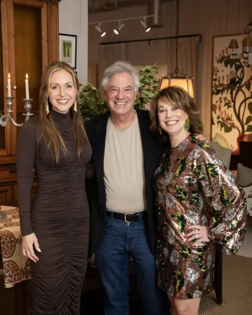 Three people smiling in a room with artwork and furniture.