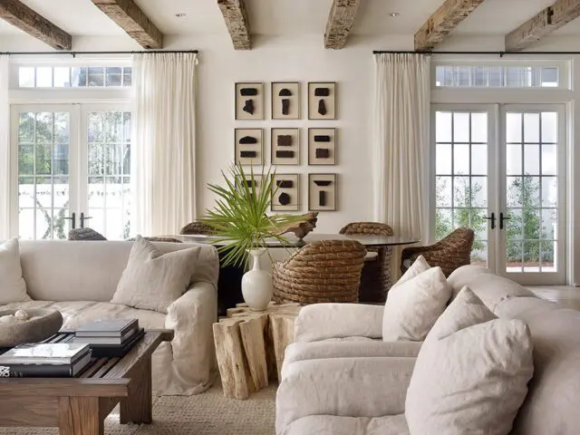 Living room with linen sofas, exposed wood beams, and French doors opening to a garden.