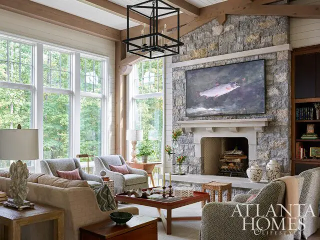 Living room with stone fireplace, large windows, and comfortable seating.