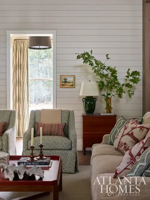Living room with patterned armchairs, neutral sofa, and shiplap walls. Atlanta Homes & Lifestyles