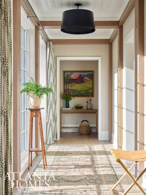 Hallway with wood beams, patterned curtains, oriental rug, and barn painting