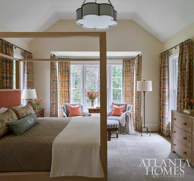 Bedroom with four-poster bed, patterned curtains, and two armchairs.