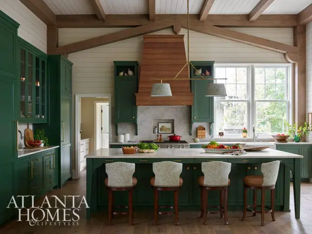 Green kitchen with marble island, wood beams, and pendant lights