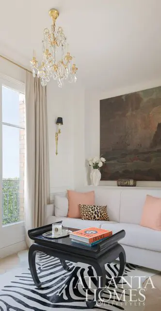 Living room with white sofa, black coffee table, zebra rug, and crystal chandelier.