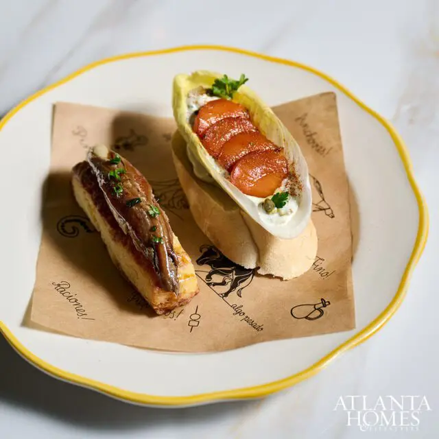 Two tapas on a plate: one with anchovies on toast, the other with fruit and cream in endive.