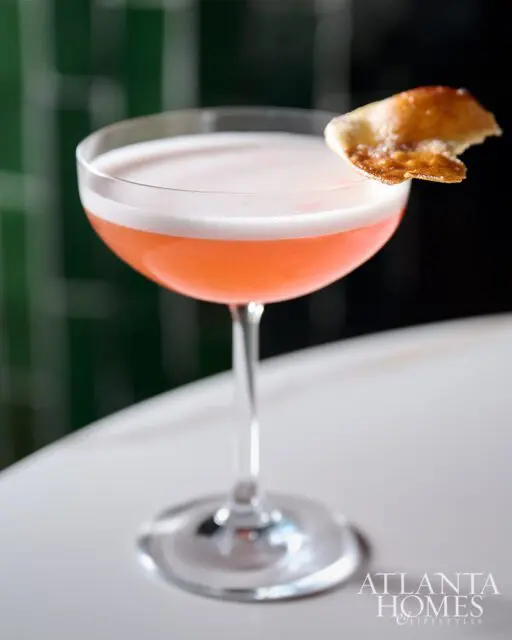 Pink cocktail with foam and a garnish in a coupe glass, Atlanta Homes & Lifestyles logo