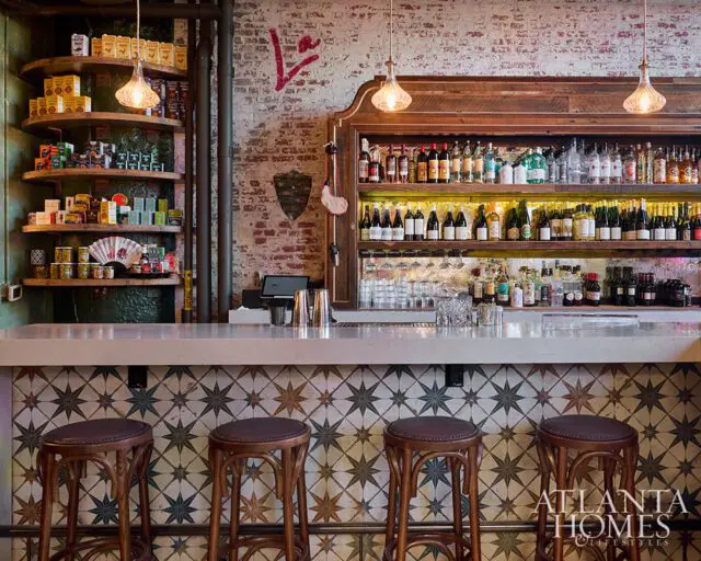 Bar with brick wall, shelves of liquor bottles, and star-patterned tile backsplash.