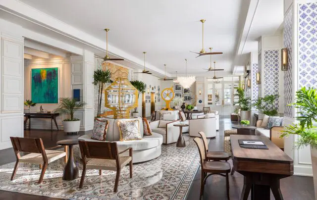 Lobby with white sofas, patterned rug, wooden chairs, and blue and white tile accents.