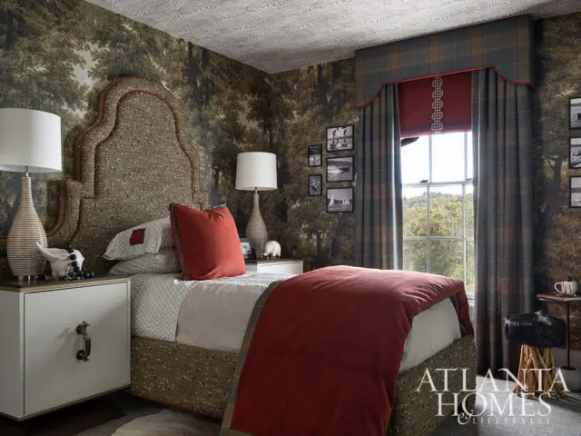 Bedroom with forest wallpaper, upholstered headboard, plaid curtains, and red bedding.
