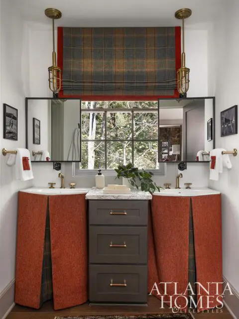 Bathroom with two sinks, dark gray vanity, and orange fabric skirted bases.