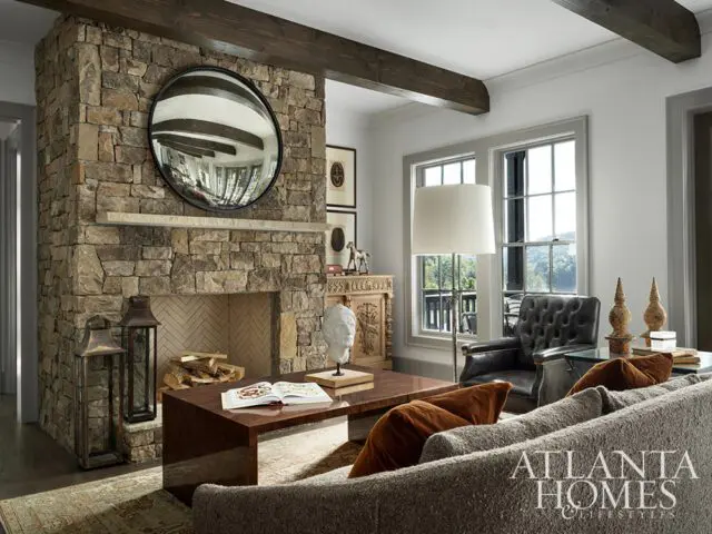 Living room with stone fireplace, tufted leather armchair, and sectional sofa.