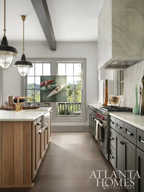 Kitchen with gray cabinets, marble countertops, wood island, and pendant lights.