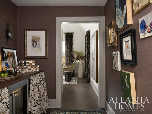 Hallway with dark textured walls, framed art, and a doorway leading to a living room with patterned