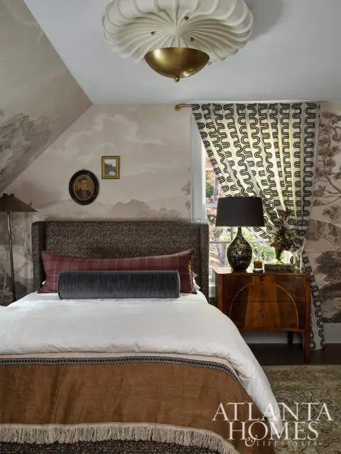 Bedroom with landscape wallpaper, patterned curtains, and a bed with brown and white bedding.