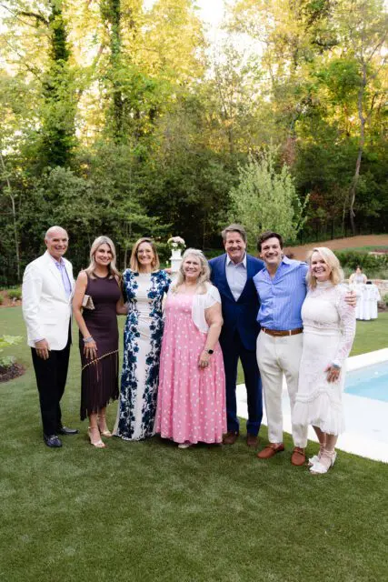 Group of seven people posing for a photo outdoors by a pool.