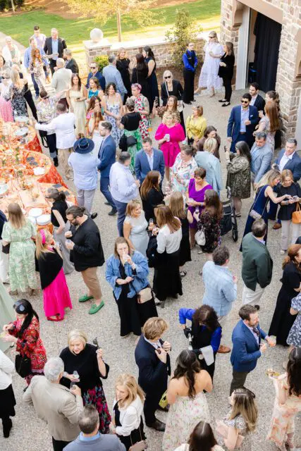 Aerial view of a crowded outdoor event with people mingling near food tables.