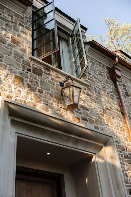 Stone house exterior with open casement windows and copper downspout