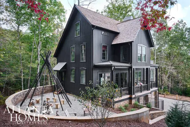 Black vertical siding house with wood shingle roof and a fire pit area