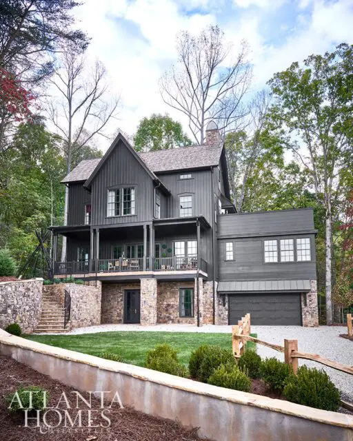 Dark gray modern farmhouse with stone foundation, covered porch, and attached garage.