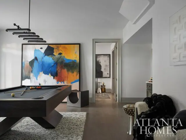 Game room with dark wood pool table, abstract art, and modern lighting.