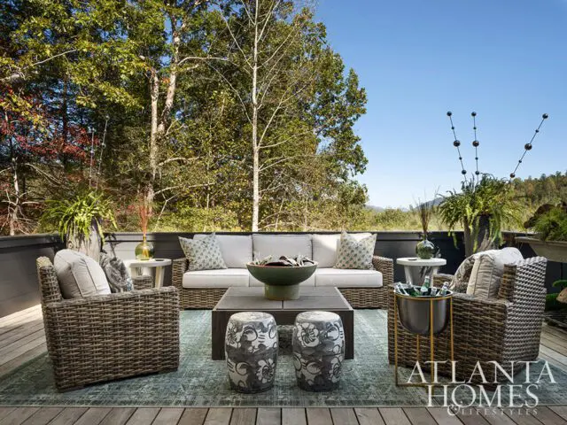 Outdoor living space with wicker furniture, patterned pillows, and a view of trees and mountains.