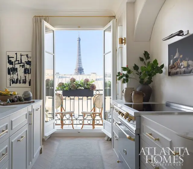 White kitchen with gold hardware, view of Eiffel Tower from balcony.