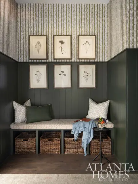 Dark green paneled walls with botanical print wallpaper and a built-in bench with storage baskets.
