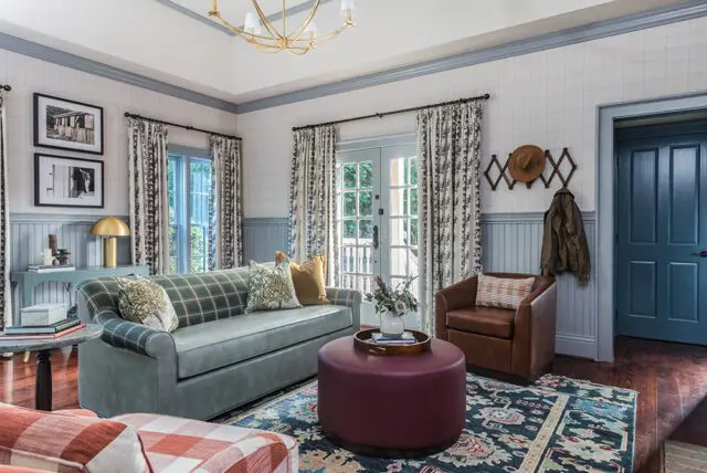 Living room with plaid sofa, leather armchair, burgundy ottoman, and patterned rug.