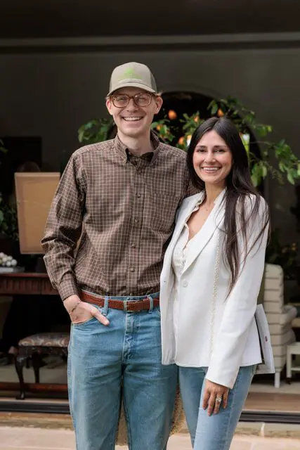 Man in plaid shirt and baseball cap with woman in white blazer