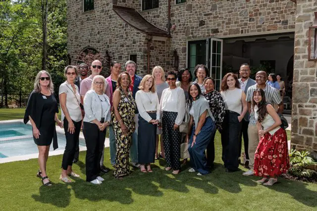Group of people standing on grass in front of a stone house
