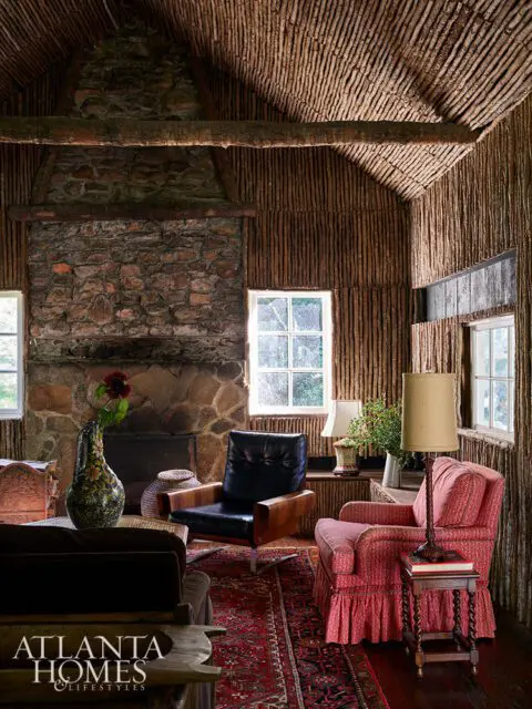 Living room with stone fireplace, wood-paneled walls, and rustic ceiling. Furniture includes