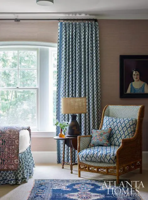 Bedroom with blue and white patterned curtains, a wicker chair with blue cushions, and a vintage