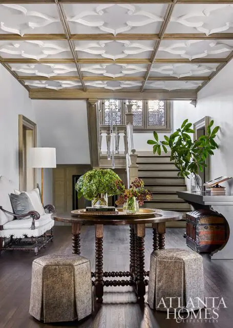 Foyer with ornate coffered ceiling, round table, and staircase.