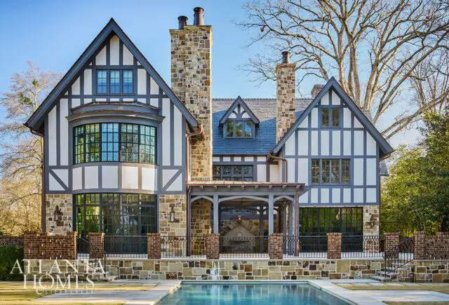 Tudor-style home with stone and white stucco exterior, dark trim, and gabled roofs.