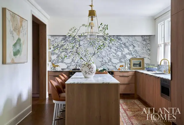 Kitchen with marble backsplash, wood cabinets, and island with marble countertop.
