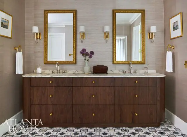 Double vanity with dark wood drawers, marble countertop, and two gold-framed mirrors.