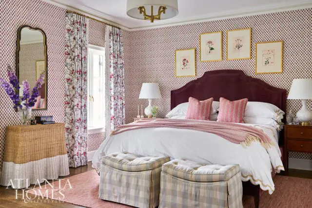 Bedroom with burgundy headboard, pink pillows, patterned wallpaper, and floral curtains.