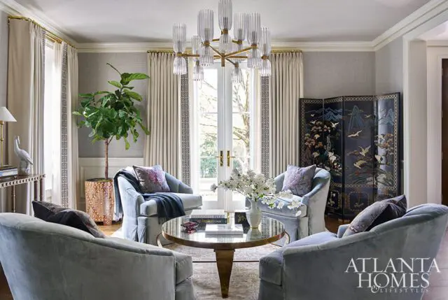 Living room with light blue velvet chairs, gold coffee table, and ornate folding screen.