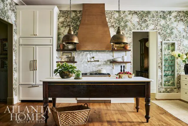 Kitchen with botanical wallpaper, brass pendant lights, and a copper range hood.