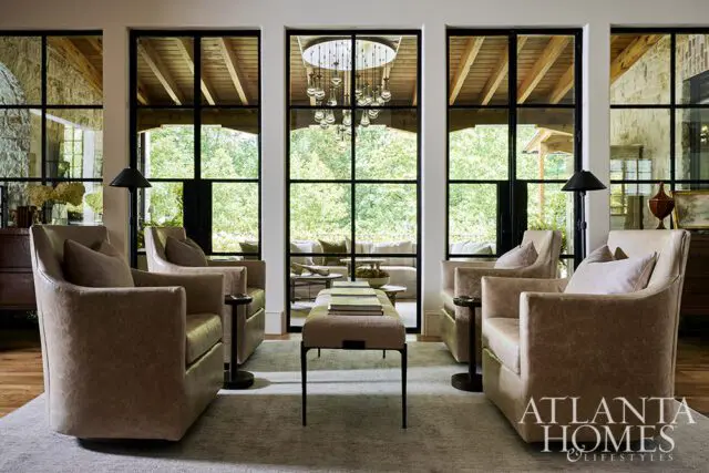 Living room with four tan leather chairs, large windows, and a chandelier