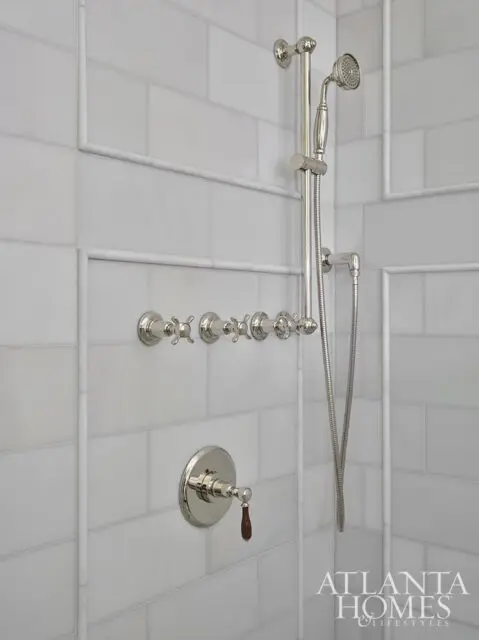 White subway tile shower with nickel fixtures and a handheld showerhead