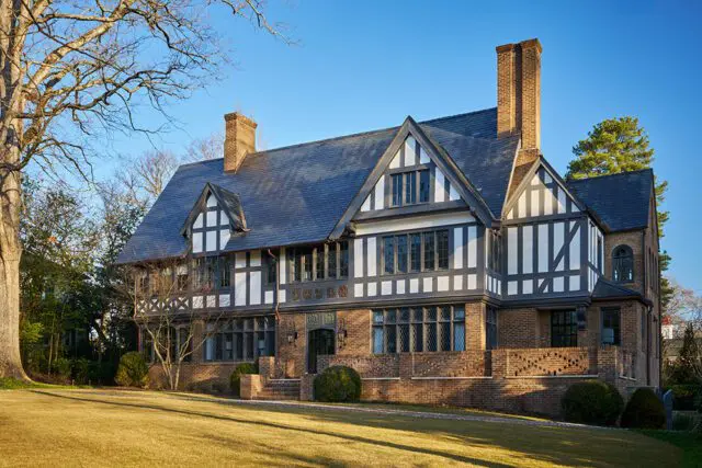 Tudor-style house with brick facade, dark slate roof, and white timber framing.