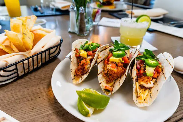 Three fish tacos with pico de gallo, avocado, jalapeños, and cilantro