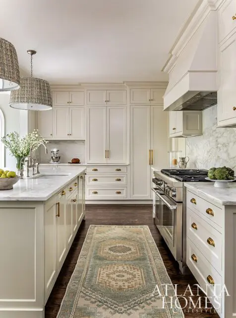 Cream kitchen with marble countertops, brass hardware, and stainless steel range.