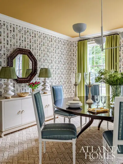 Dining room with floral wallpaper, yellow ceiling, green curtains, and blue striped chairs.